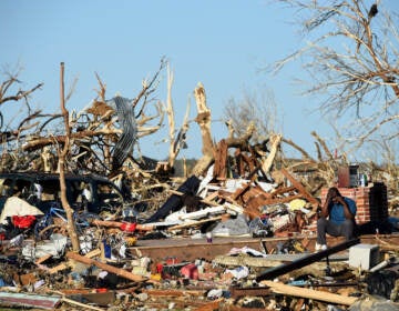 A man sits among the wreckage caused by a series of powerful storms and at least one tornado on March 25, 2023 in Rolling Fork, Mississippi