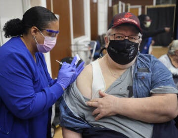 A medical professional gives someone a COVID-19 vaccine.