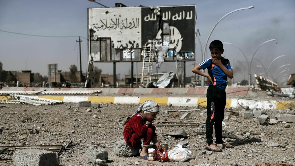 Iraqi children sit amid rubble in a street in Mosul.