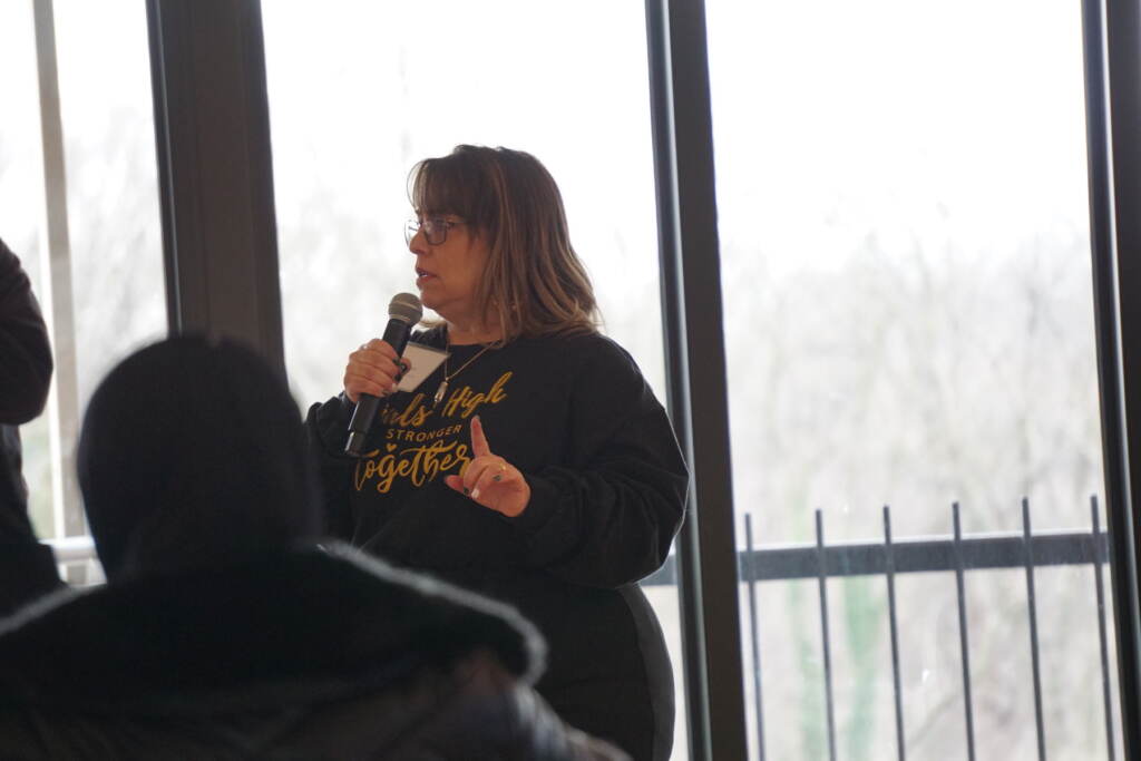 Woman standing in front of a group and speaking into a microphone