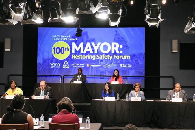 A row of Philadelphia mayoral candidates are seated at a stage in front of an audience.