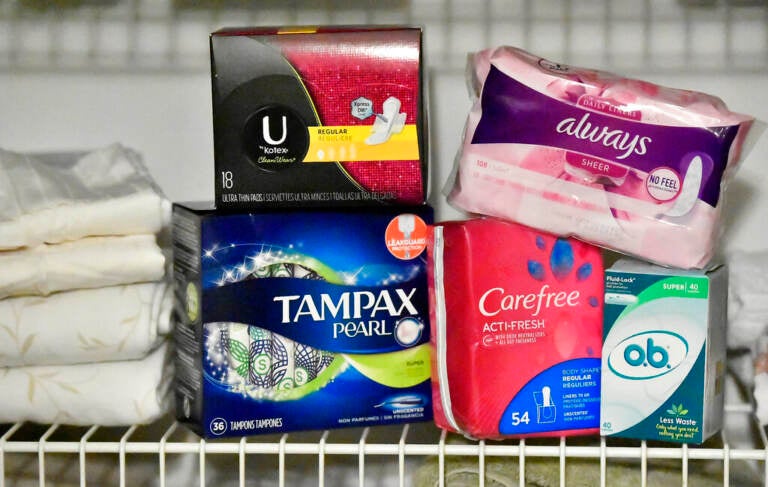 Several boxes of pads and tampons are arranged on a shelf.