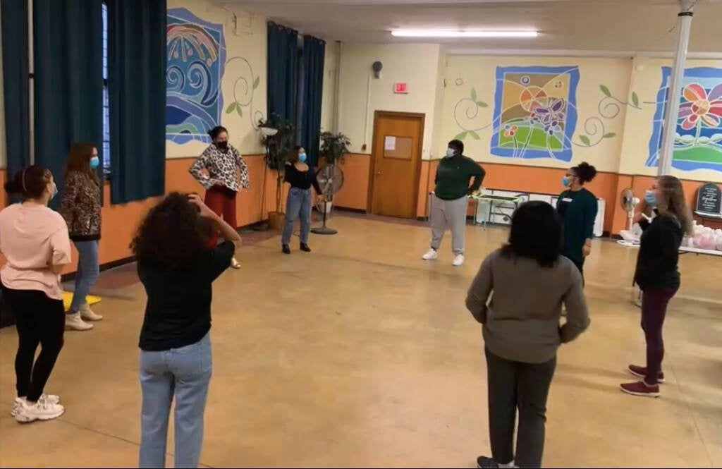 A group of people stand in a circle in a room.