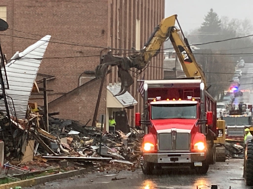 A fire truck outside of rubble on a street.