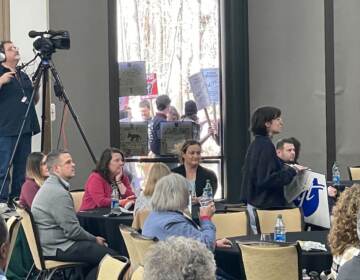 Protesters are visible through the windows of a meeting room.