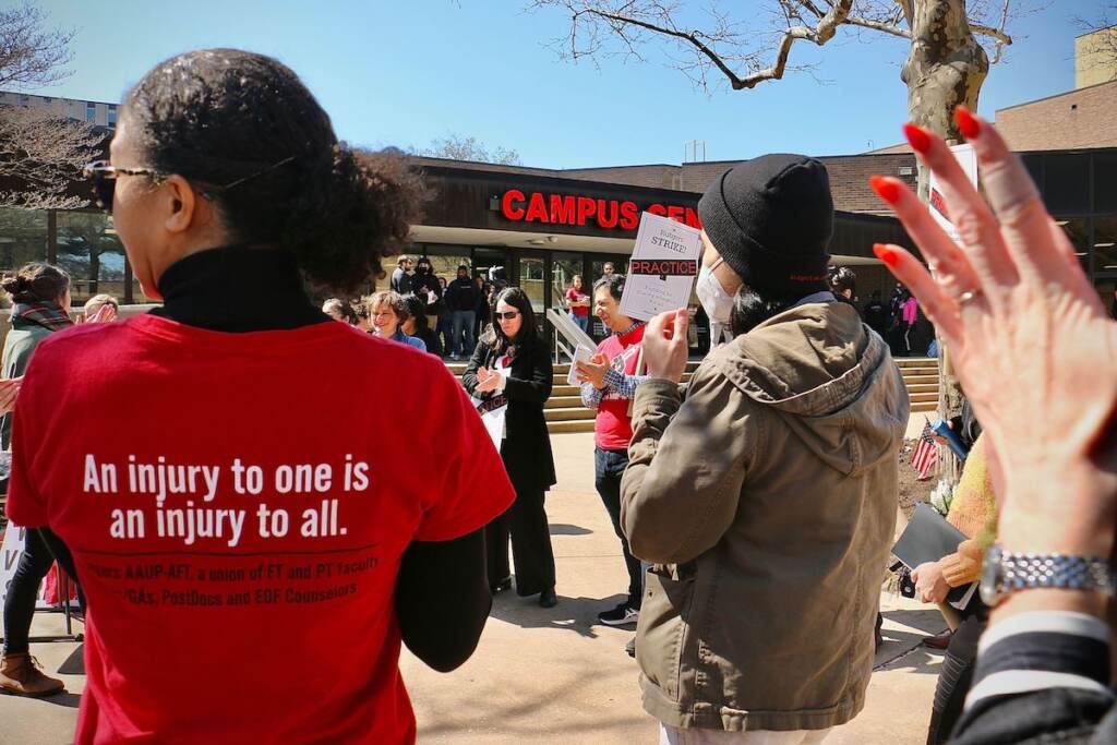 People hold picket signs in front of the campus center.