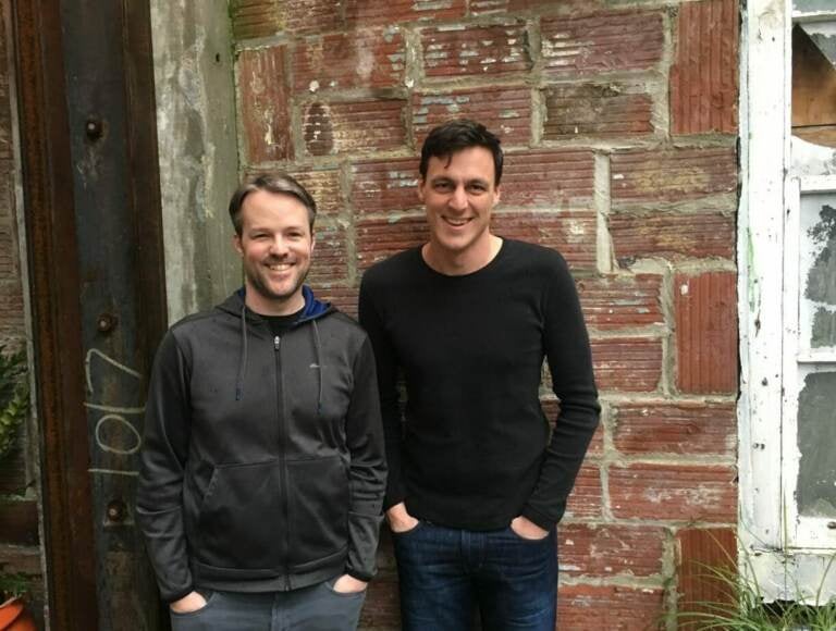Bede Jordan and Stefan Kalb pose for a photo in front of a brick wall.