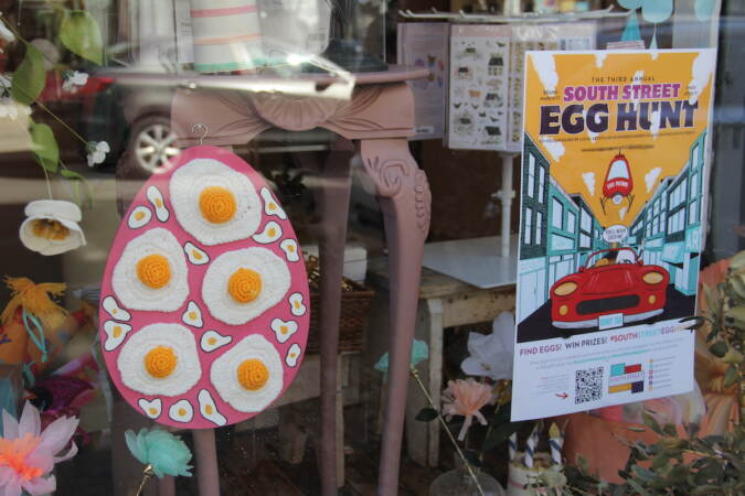 An egg design is pasted in a store window along with a sign advertising the South Street Egg Hunt.