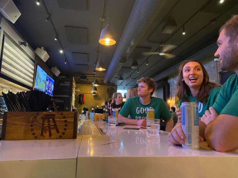 People wearing green sit at a bar.