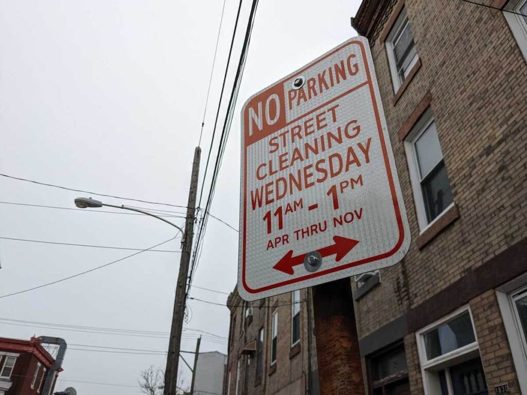 A close-up of a sign that reads "No Parking, Street Cleaning Wednesday 11 a.m. - 1 p.m.".