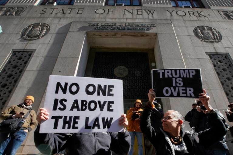 People hold up signs, including one that says 