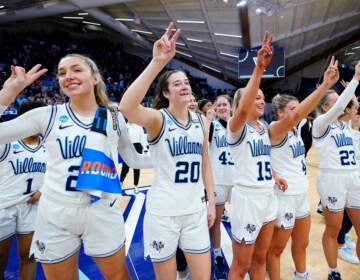 Villanova players stand together, arms upraised, celebrating after a victory.