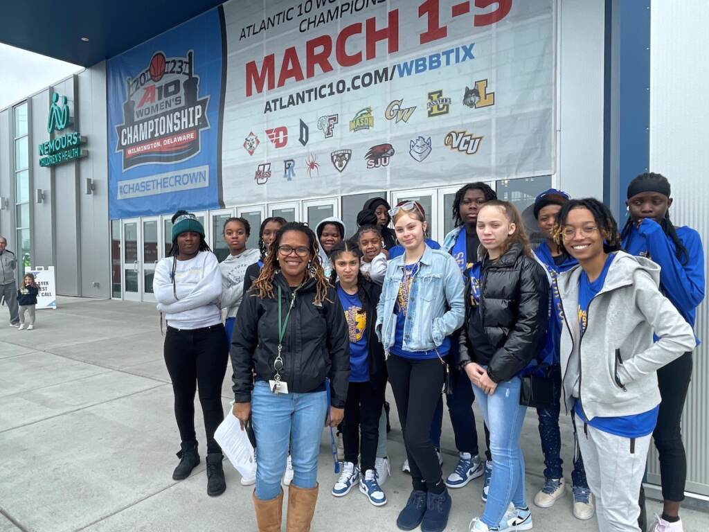 Faythe Daniels and a group of students pose for a photo outside of an arena.