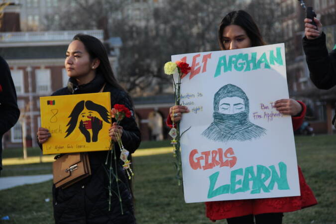 Two people hold signs advocating for women's rights in Afghanistan and beyond.