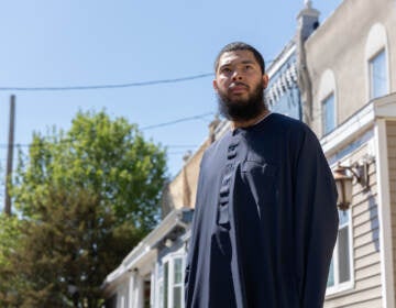 Anthony Freeman looks off into the distance. Behind him are trees and a row of houses.