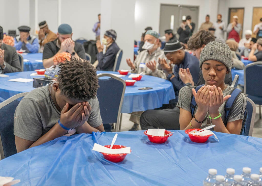 Hakeem Greer-Gilliam (left) and Rahsaan Mason observe prayers before breaking the fast at the Baitul Aafiyat Mosque's Interfaith Iftkar on Saturday evening