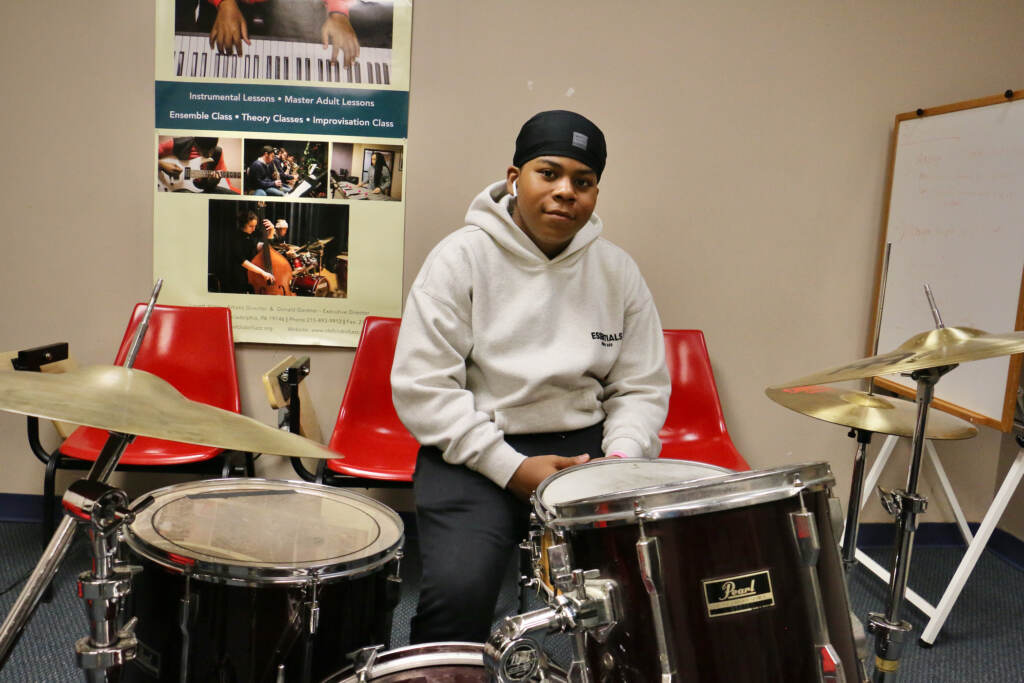 Elijah Barnes sits behind a drum set, smiling slightly.