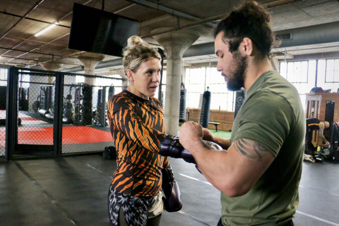 Daishi Goto (right) helps DeAnna Bennett with her gloves during a practice session at Marquez MMA Gym