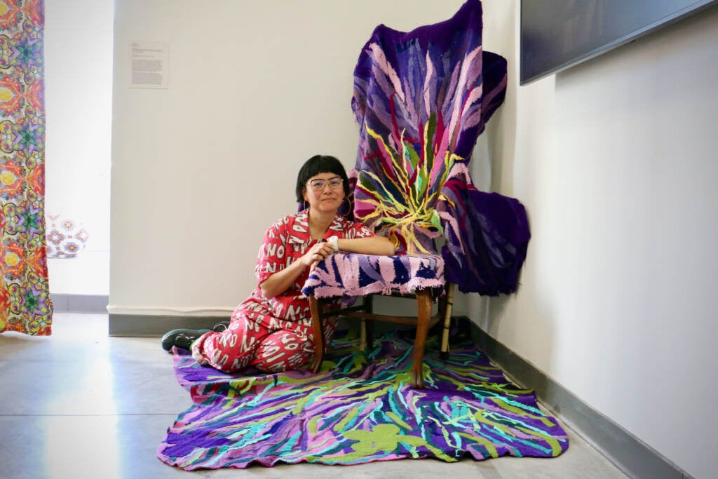 Anne Ishii is seated in a decorated room.