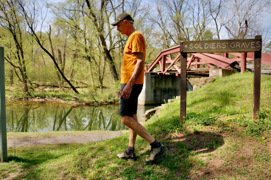 Neil King walking on a path towards the gravesite.