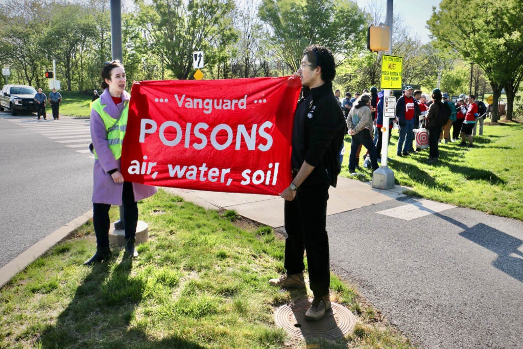 Activists hold a sign that reads "Vanguard poisons air, water, soil"