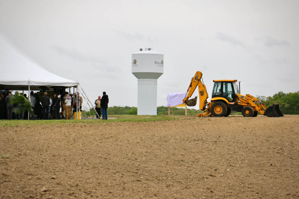 An excavator works in an open field.