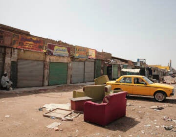A man sits by shuttered shops in Khartoum