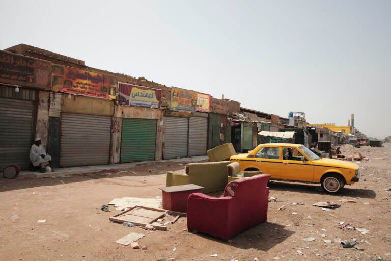 A man sits by shuttered shops in Khartoum