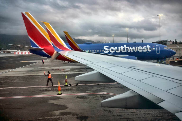 A Southwest Airlines ground crew directs a plane out of the terminal at Hollywood Burbank Airport in Burbank