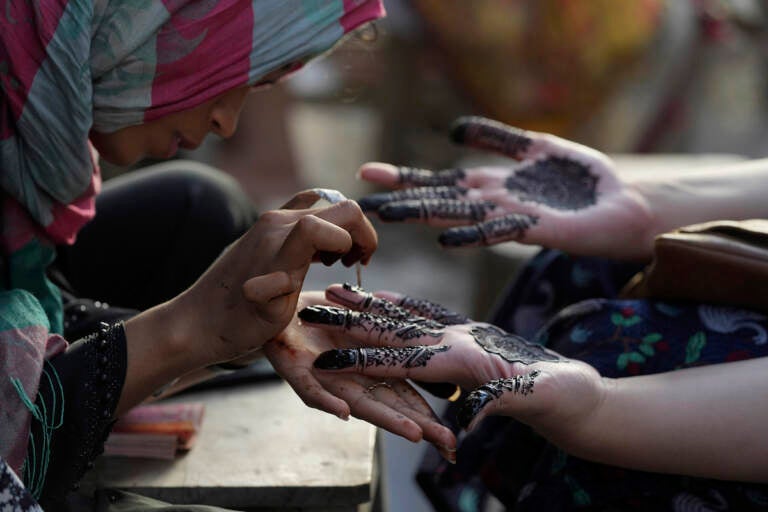 Pakistan Beautician paints customers hands for Eid al-Fitr