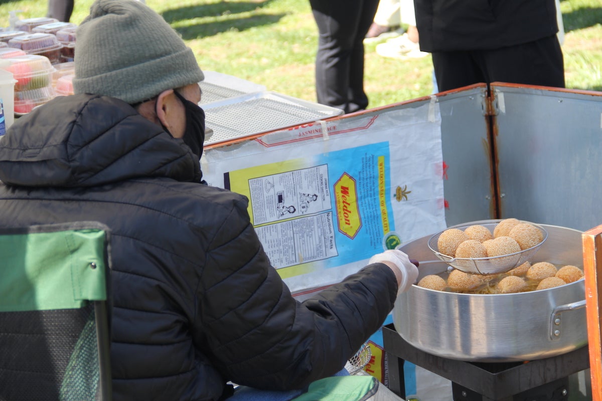 A vendor fries sesame-covered dough balls.