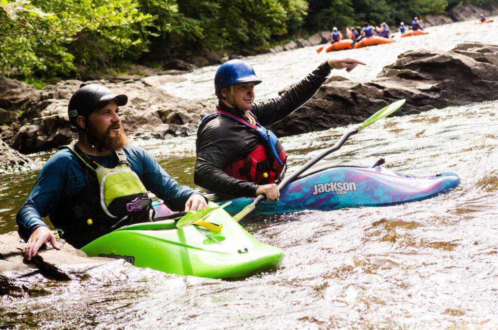 2 men kayaking on a river.