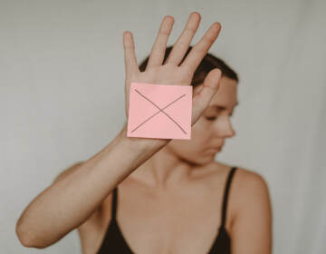 Woman holding post it note with the letter X drawn on it