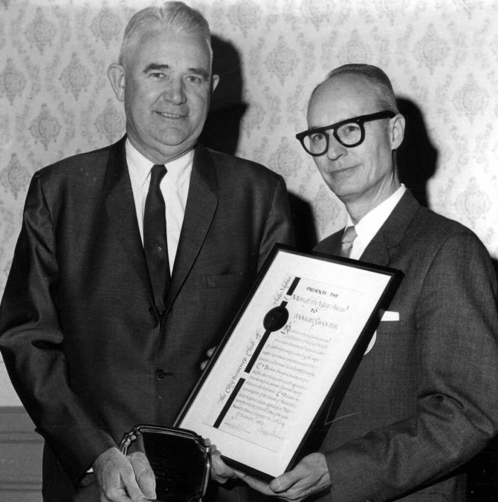 Samuel Baxter poses for a photo with another person and an award.