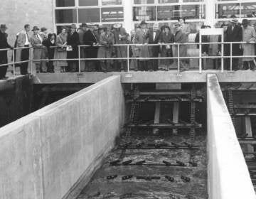 A black-and-white photo of people overlooking a sewage plant.