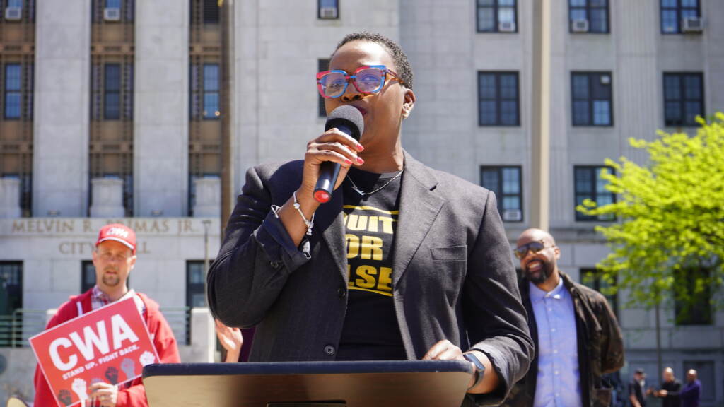 Someone speaking into a microphone at a rally.