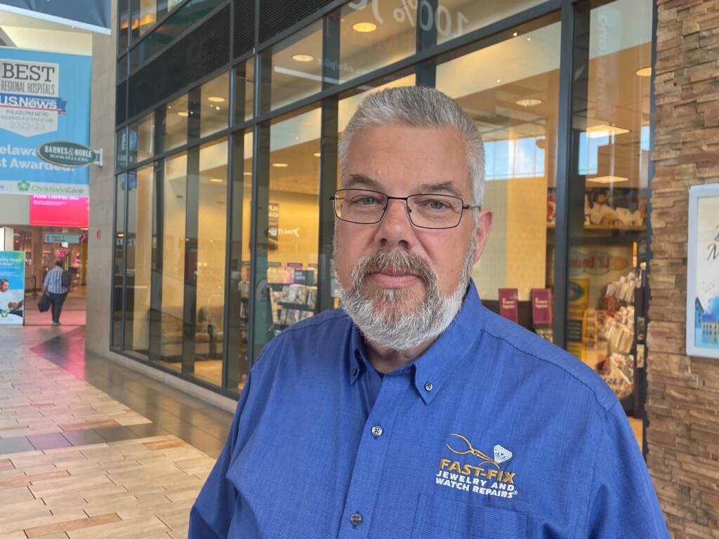 Man standing in front of a store in a mall.