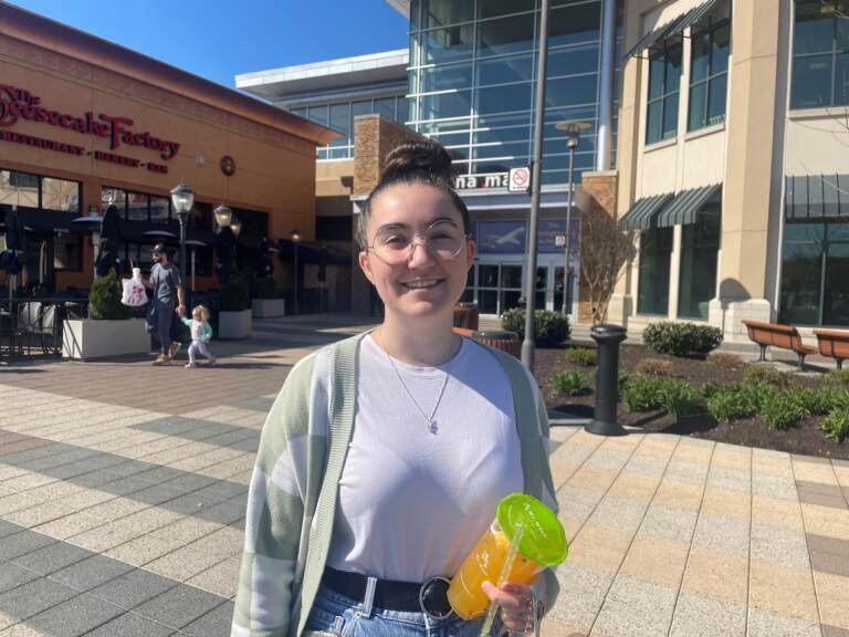 A woman standing outside in front of a mall.