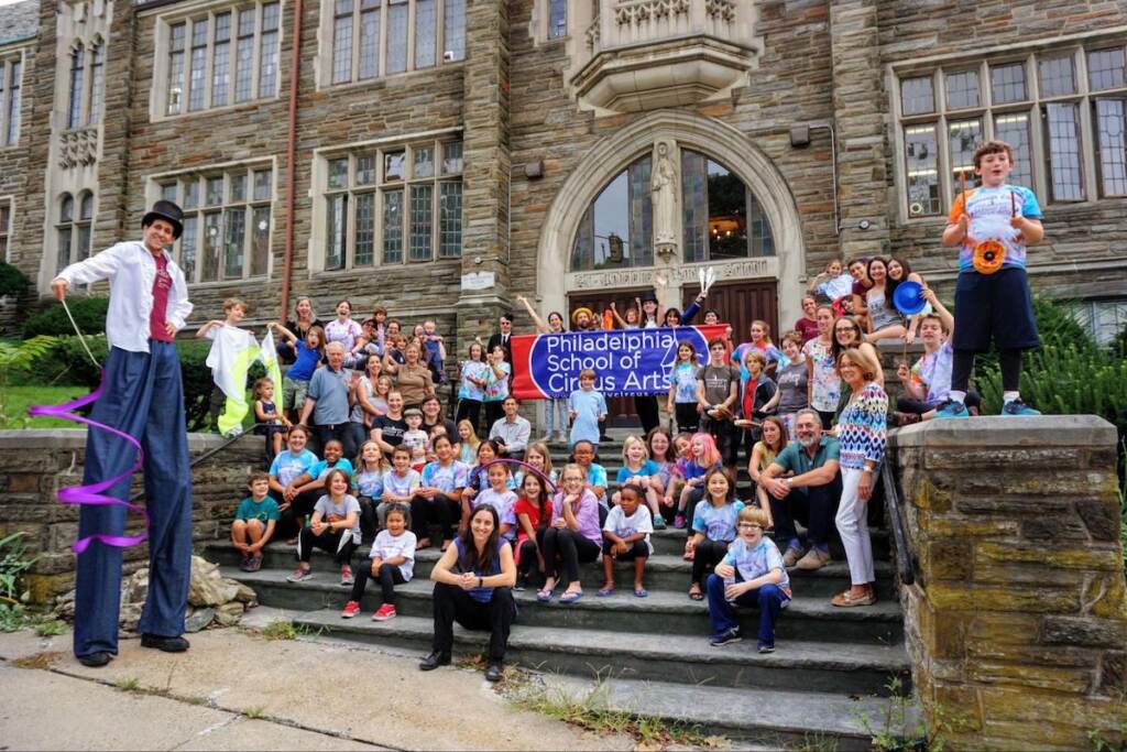 A group of people pose on a staircase outside of a building.