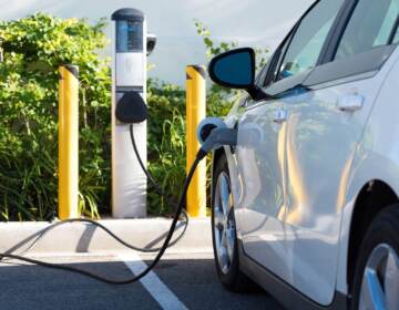 An up-close view of an electric car that's connected to an EV charging station.