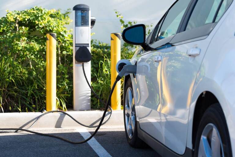 An up-close view of an electric car that's connected to an EV charging station.