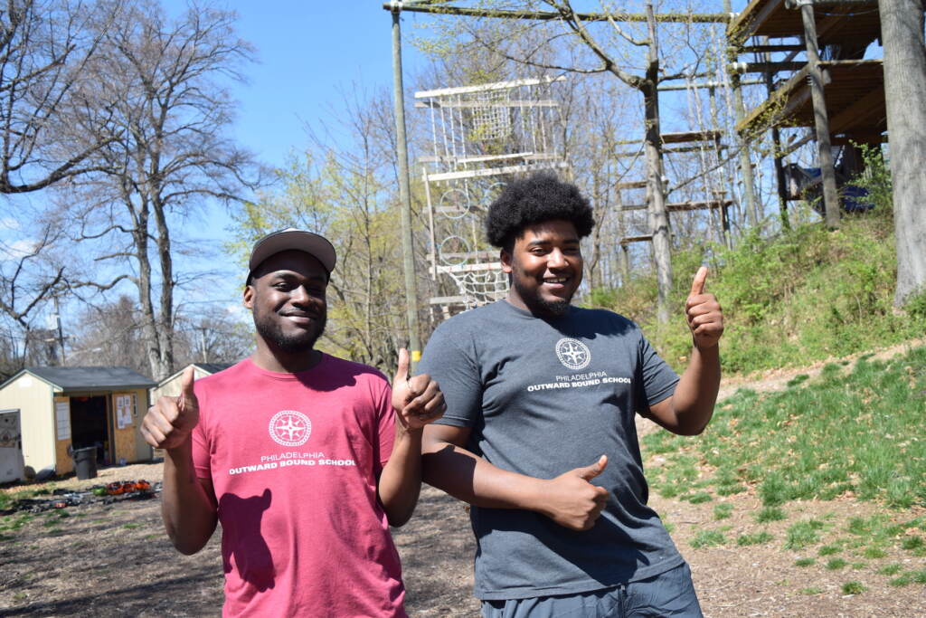 2 young men posing outside.