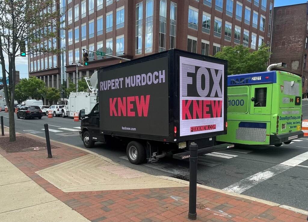 "Rupert Murdoch knew" is written on the side of a truck.