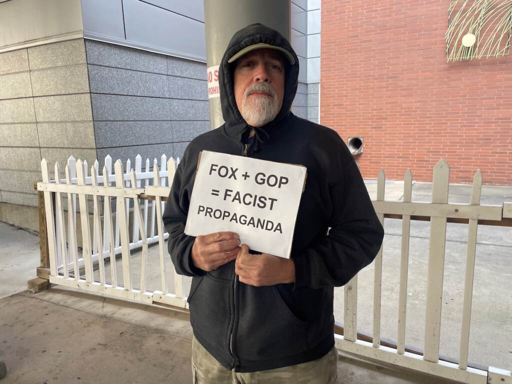 Bill Schultz holds a sign.