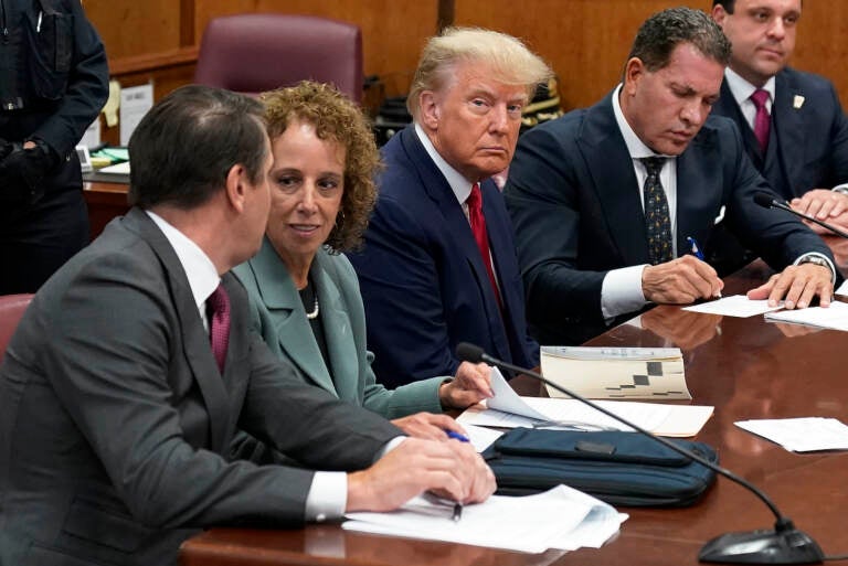 Former President Donald Trump sits at the defense table with his defense team in a Manhattan court