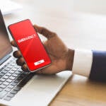 A person holds a phone with a red screen and a box that reads 