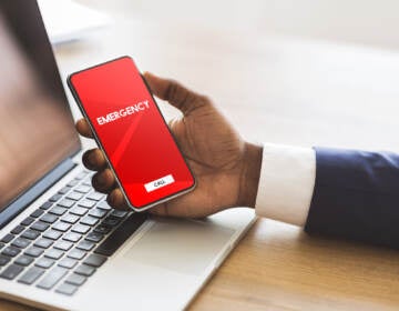 A person holds a phone with a red screen and a box that reads 