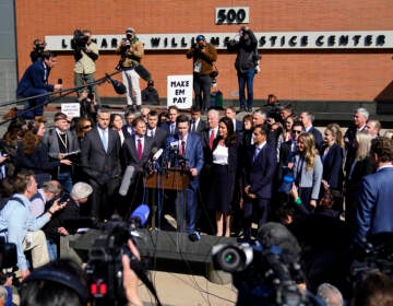 People stand in a group surrounded by cameras and news reporters.