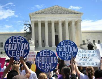 People hold signs reading keep abortion legal outside of the Supreme Court.