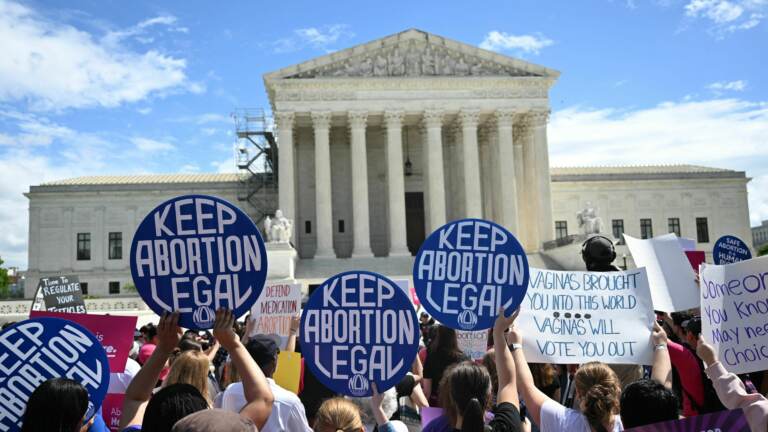 People hold signs reading keep abortion legal outside of the Supreme Court.